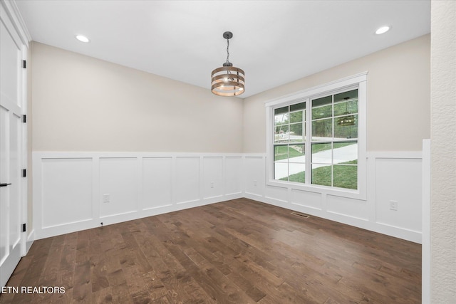 spare room with an inviting chandelier and dark hardwood / wood-style floors