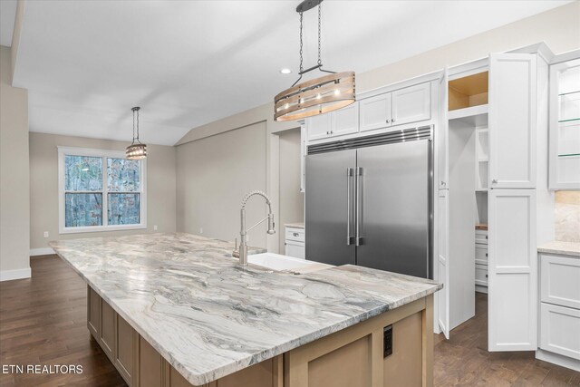 kitchen with white cabinets, dark hardwood / wood-style flooring, built in fridge, and an island with sink