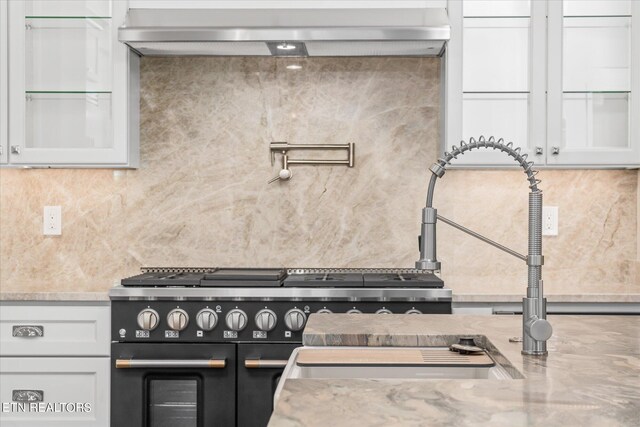 kitchen with white cabinets, light stone counters, and double oven range