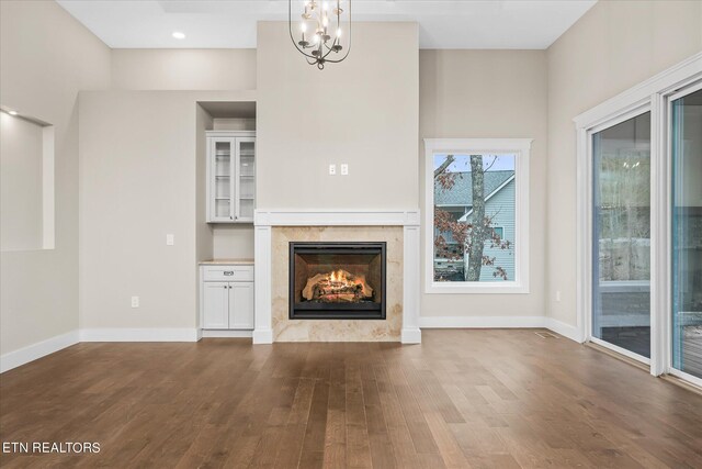 unfurnished living room featuring a chandelier, hardwood / wood-style flooring, and a high end fireplace