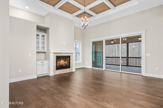 unfurnished living room featuring an inviting chandelier, a towering ceiling, dark wood-type flooring, and coffered ceiling