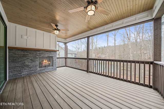 wooden terrace with ceiling fan and an outdoor stone fireplace