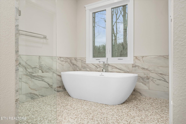 bathroom featuring a bath and tile walls