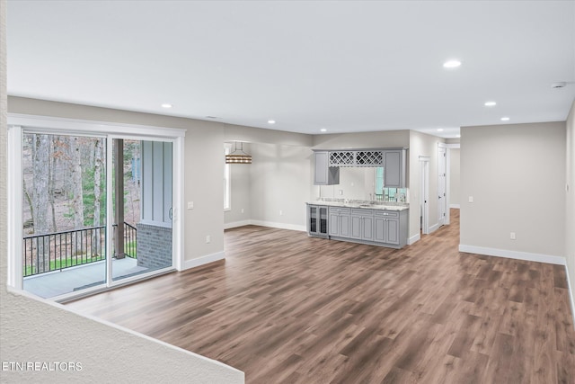 unfurnished living room with beverage cooler, dark hardwood / wood-style flooring, and wet bar