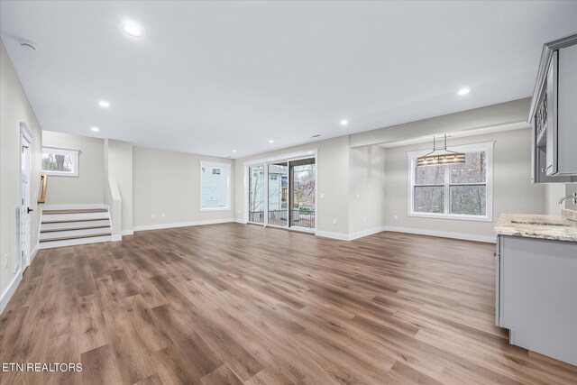 unfurnished living room featuring sink, hardwood / wood-style floors, and a wealth of natural light