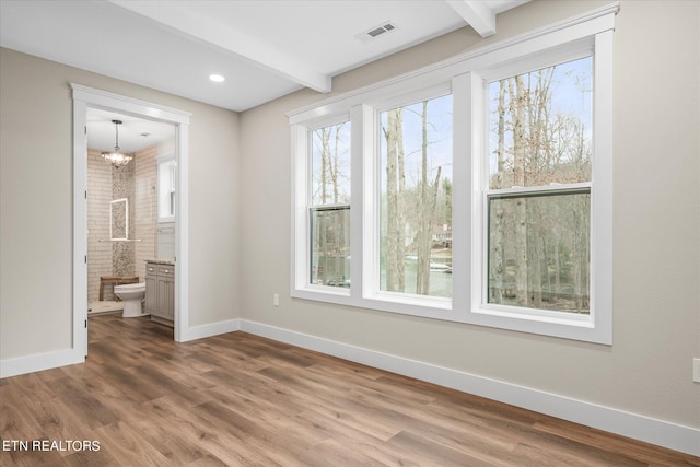 empty room with beamed ceiling, hardwood / wood-style flooring, and a notable chandelier