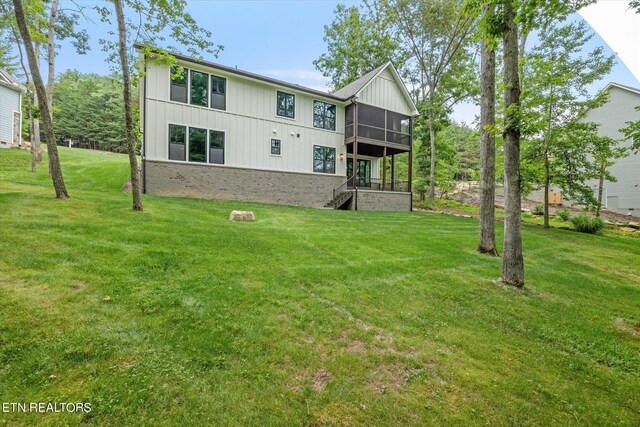 rear view of property featuring a sunroom and a lawn