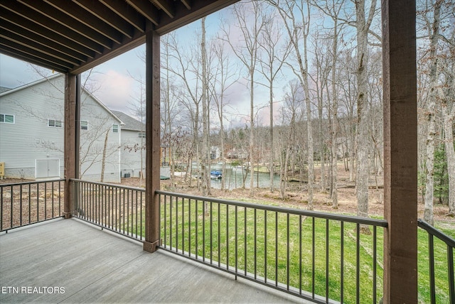 wooden terrace with a water view and a lawn