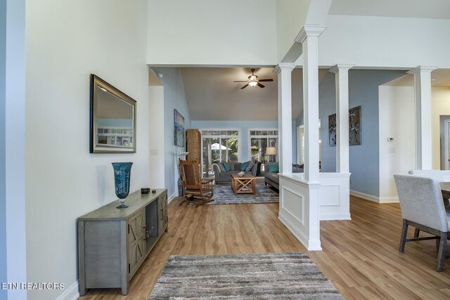 entrance foyer featuring ceiling fan, a towering ceiling, light hardwood / wood-style flooring, and ornate columns