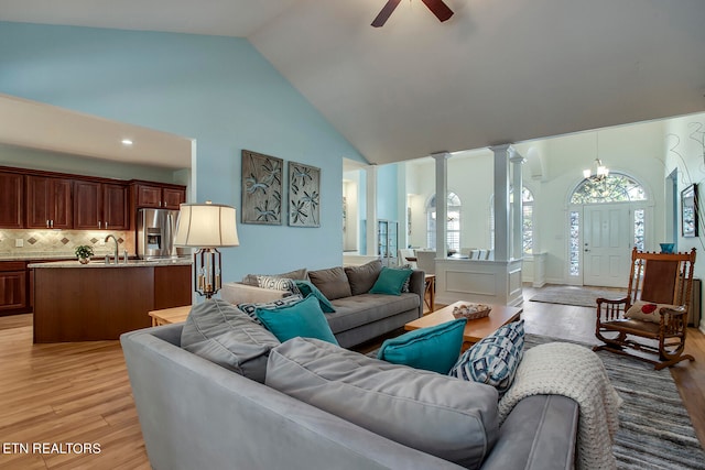 living room featuring decorative columns, high vaulted ceiling, light hardwood / wood-style floors, ceiling fan, and sink