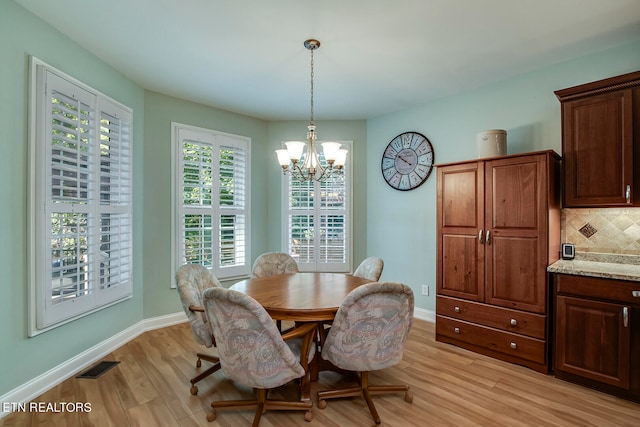 dining space with light hardwood / wood-style flooring, an inviting chandelier, and a wealth of natural light