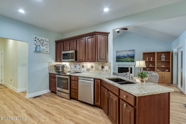 kitchen featuring lofted ceiling, stainless steel appliances, backsplash, light hardwood / wood-style flooring, and kitchen peninsula