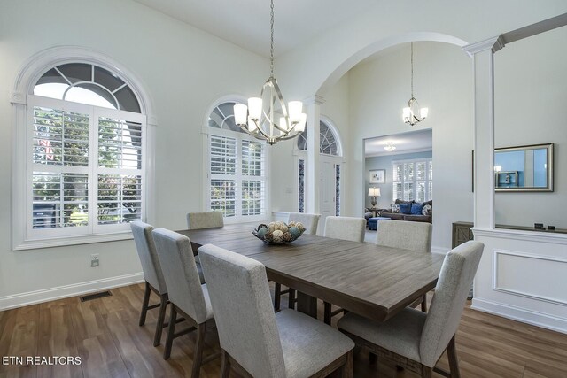 dining room featuring dark wood-type flooring, ornate columns, and a chandelier