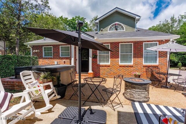 back of house with a hot tub, a patio area, and a fire pit