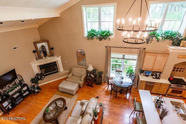 living room with crown molding, light hardwood / wood-style flooring, and an inviting chandelier