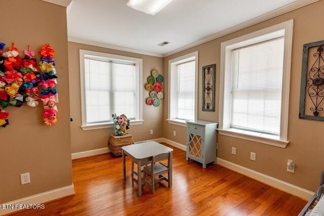 interior space with ornamental molding and hardwood / wood-style floors