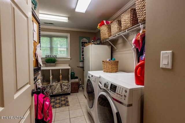 laundry room with light tile patterned flooring, washer and clothes dryer, and crown molding