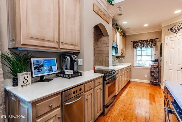 kitchen with crown molding, tasteful backsplash, light wood-type flooring, appliances with stainless steel finishes, and sink