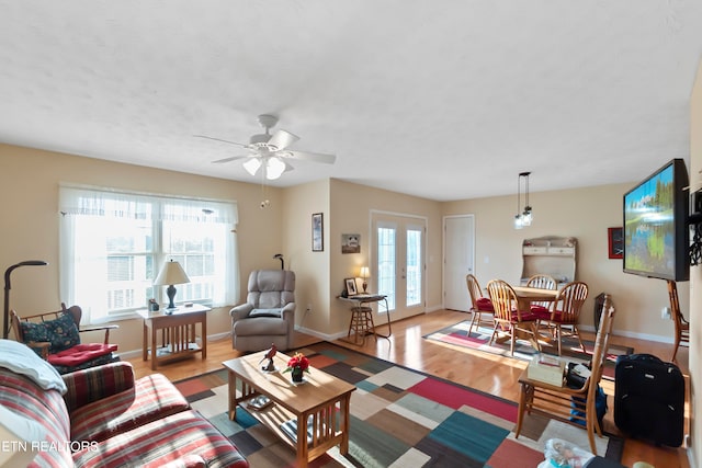 living room featuring light hardwood / wood-style flooring, ceiling fan, and french doors