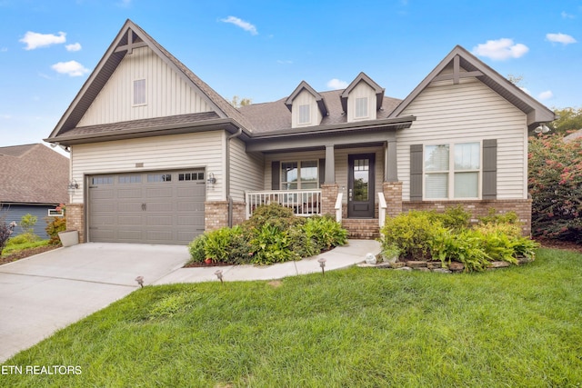 view of front of property with brick siding, a porch, a front yard, a garage, and driveway