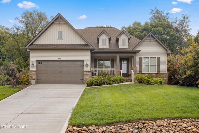 craftsman-style house with covered porch, a garage, and a front yard