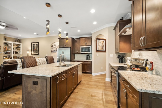 kitchen featuring a center island with sink, open floor plan, stainless steel appliances, pendant lighting, and a sink