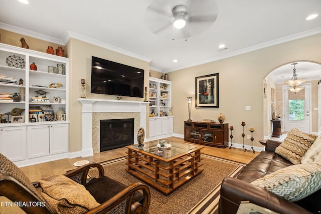 living room featuring ornamental molding, arched walkways, and light wood finished floors