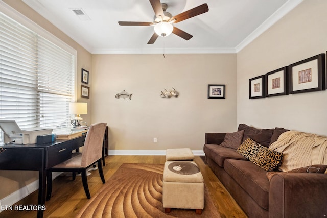 living room featuring a ceiling fan, visible vents, baseboards, ornamental molding, and dark wood finished floors