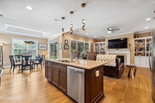 kitchen with dishwasher, an island with sink, light stone countertops, pendant lighting, and a sink