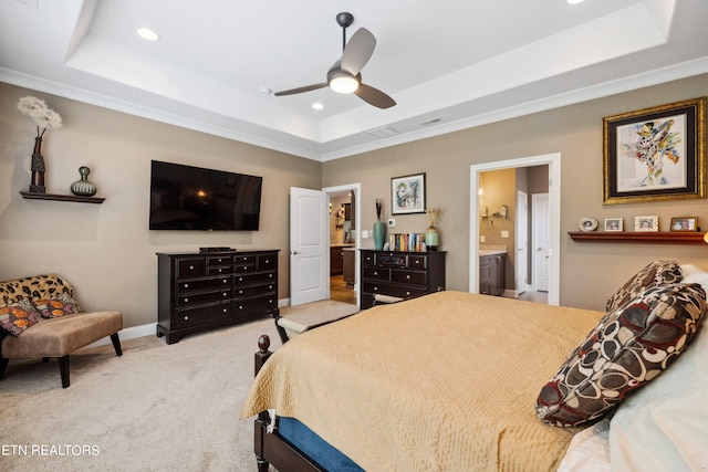 bedroom with a tray ceiling, recessed lighting, light colored carpet, ensuite bath, and baseboards