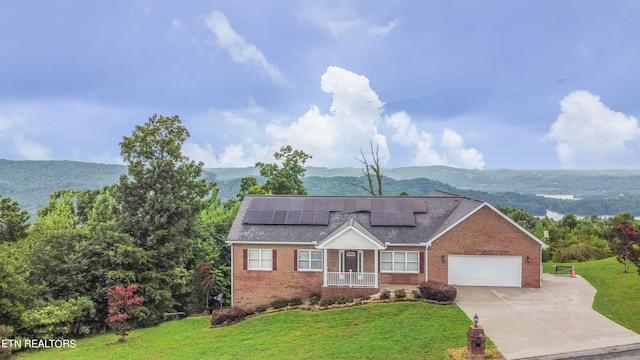 view of front of house with a mountain view, solar panels, a garage, and a front lawn