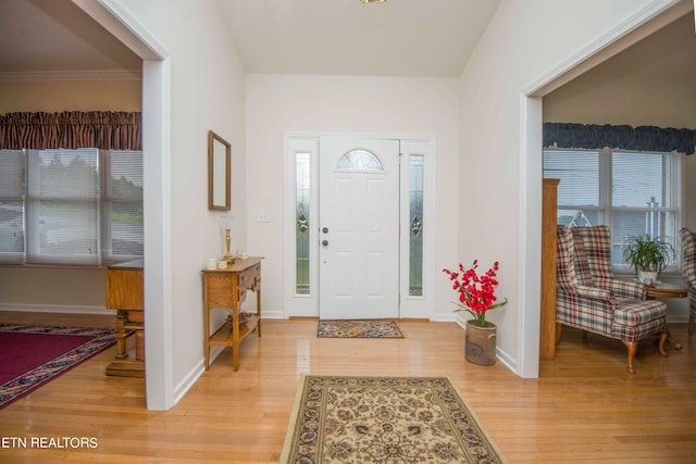 entrance foyer with crown molding and light hardwood / wood-style flooring