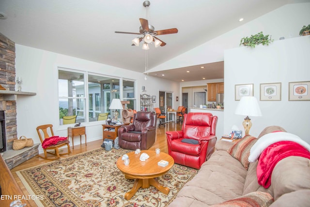 living room with a stone fireplace, hardwood / wood-style flooring, high vaulted ceiling, and ceiling fan