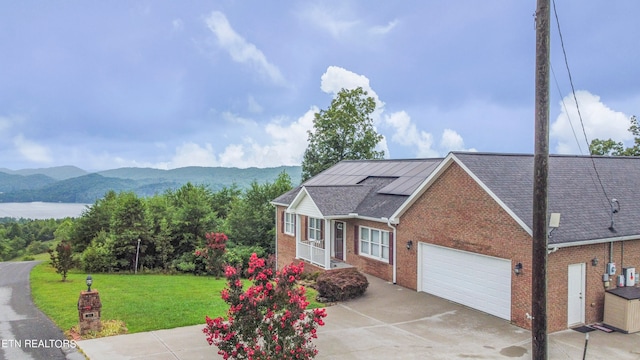 view of front of property featuring a garage, a front lawn, and a mountain view