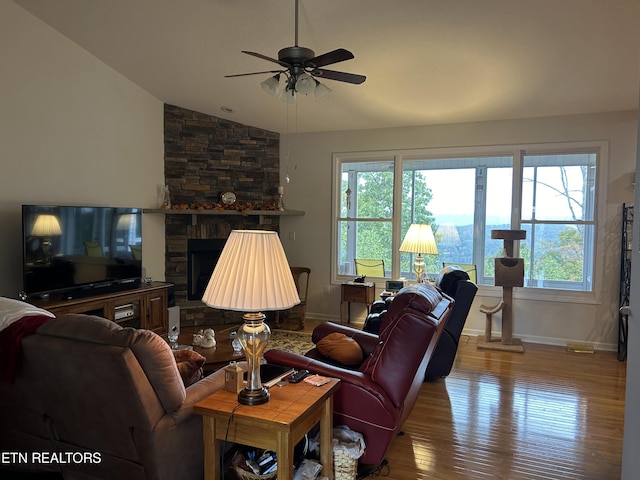 living room featuring lofted ceiling, a fireplace, wood-type flooring, and ceiling fan