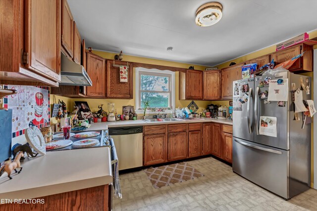 kitchen with appliances with stainless steel finishes, sink, and wall chimney range hood