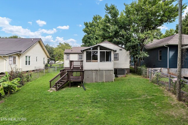 rear view of house with central AC unit, a sunroom, and a lawn