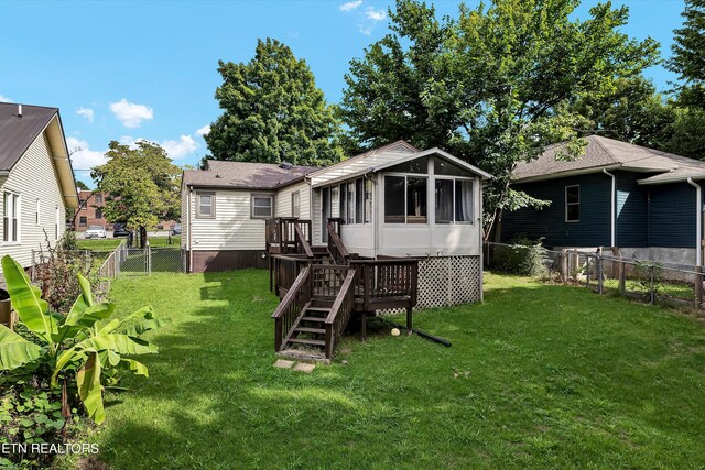 back of house featuring a sunroom, a lawn, and a deck