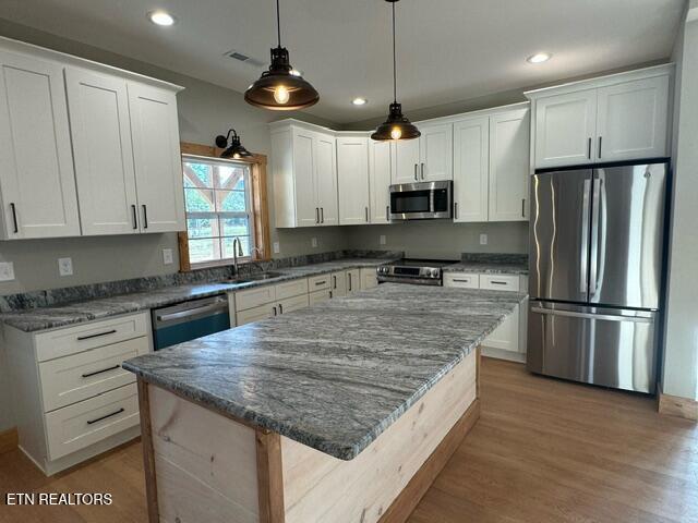 kitchen featuring white cabinets, sink, light wood-type flooring, appliances with stainless steel finishes, and a kitchen island