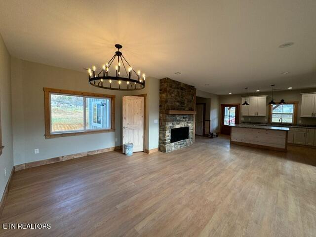 unfurnished living room with a chandelier, a fireplace, and hardwood / wood-style floors