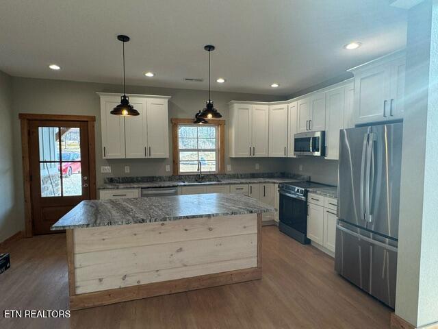 kitchen with appliances with stainless steel finishes, a center island, plenty of natural light, and hanging light fixtures