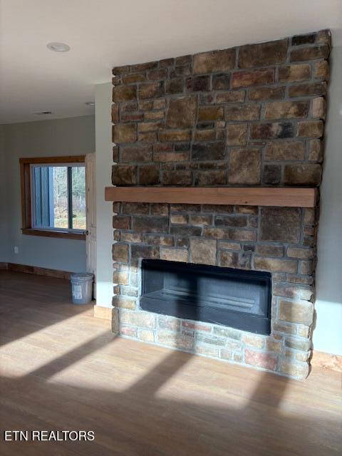 interior details with hardwood / wood-style flooring and a stone fireplace