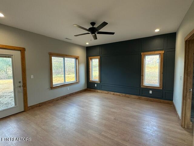 unfurnished room with a wealth of natural light, ceiling fan, and light hardwood / wood-style floors