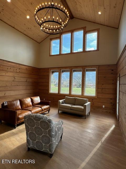 living room with wooden ceiling, high vaulted ceiling, beam ceiling, wood-type flooring, and a chandelier