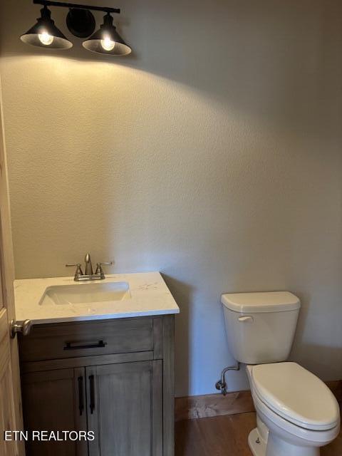 bathroom with hardwood / wood-style flooring, vanity, and toilet