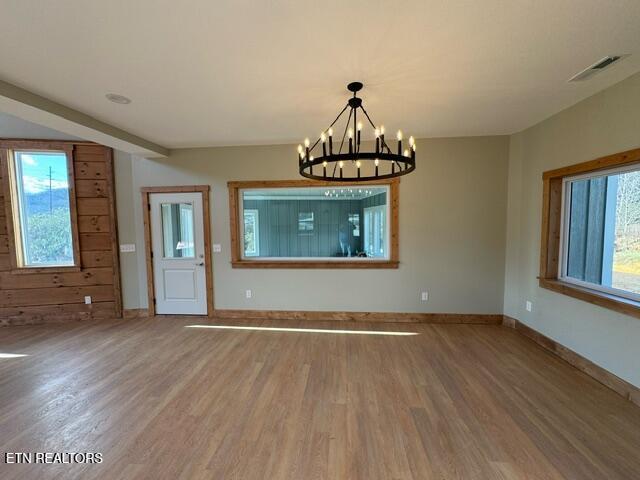 unfurnished dining area with hardwood / wood-style floors and an inviting chandelier