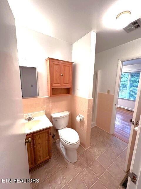 bathroom with vanity, tile walls, tile patterned floors, and toilet