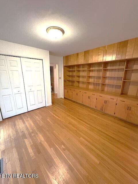 unfurnished bedroom with light wood-type flooring and a closet