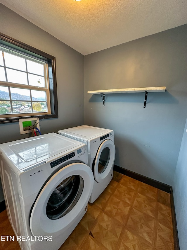 laundry area featuring light parquet floors, independent washer and dryer, and a textured ceiling