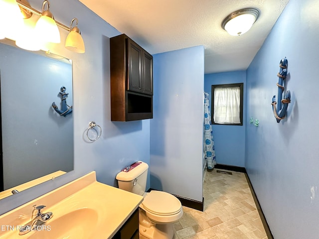 bathroom with vanity, toilet, tile patterned floors, and a textured ceiling